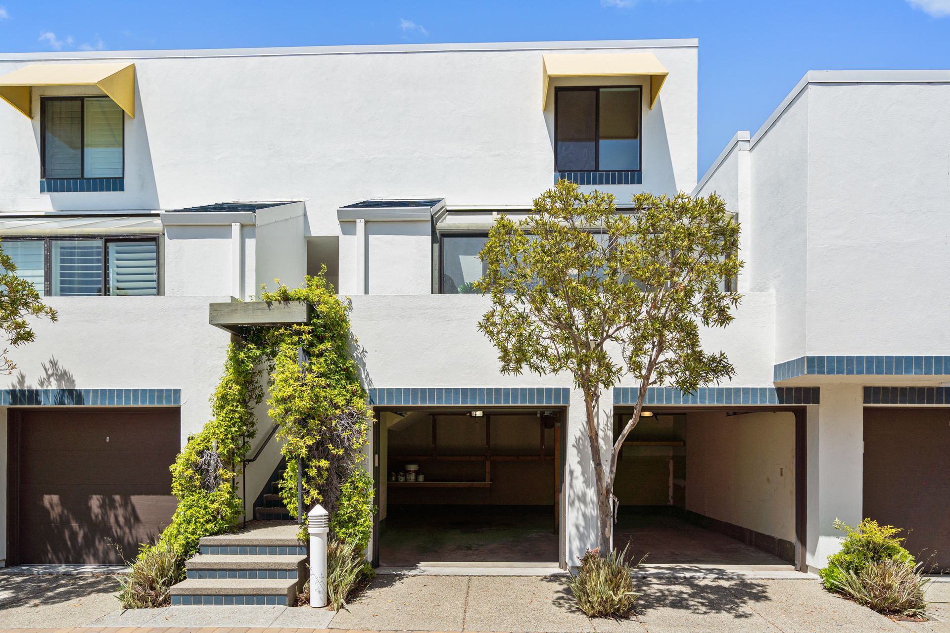 A white apartment building with a tree in front of it