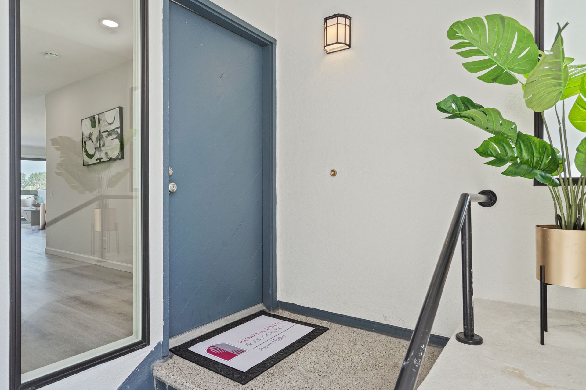 A blue door with a welcome mat in front of it and stairs leading up to it.