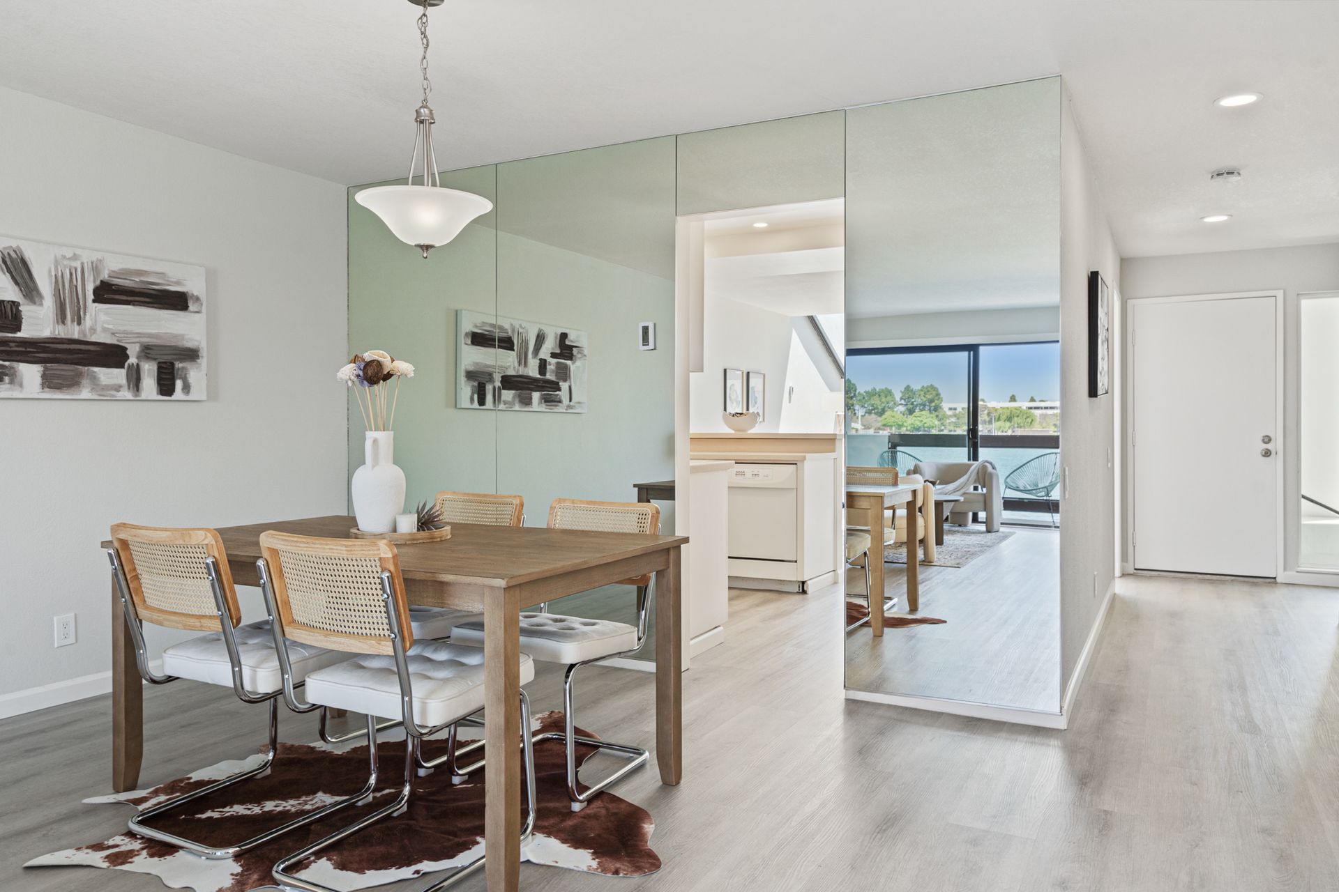 A dining room with a table and chairs and a large mirror on the wall.