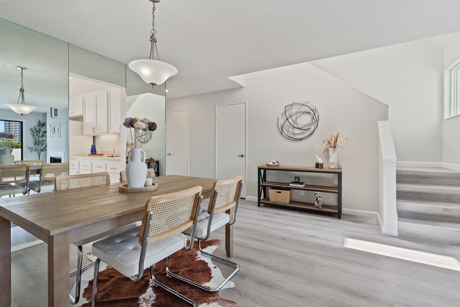 A dining room with a table and chairs and a mirror on the wall.