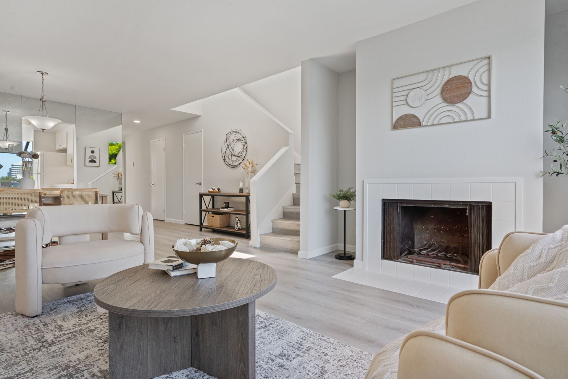 A living room with a fireplace , chairs , a coffee table and stairs.