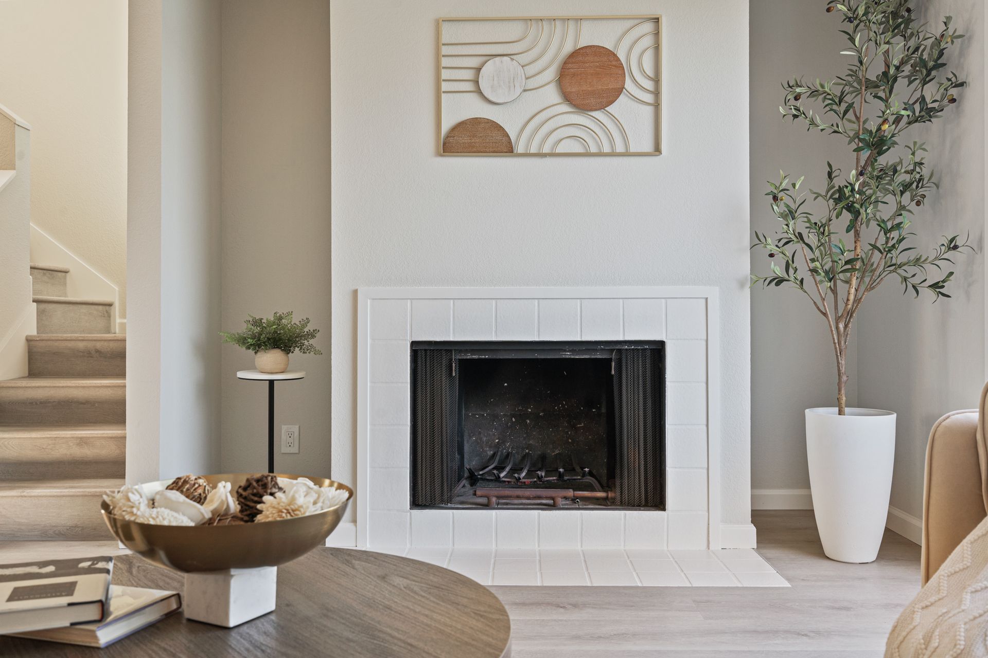 A living room with a fireplace and stairs in the background.
