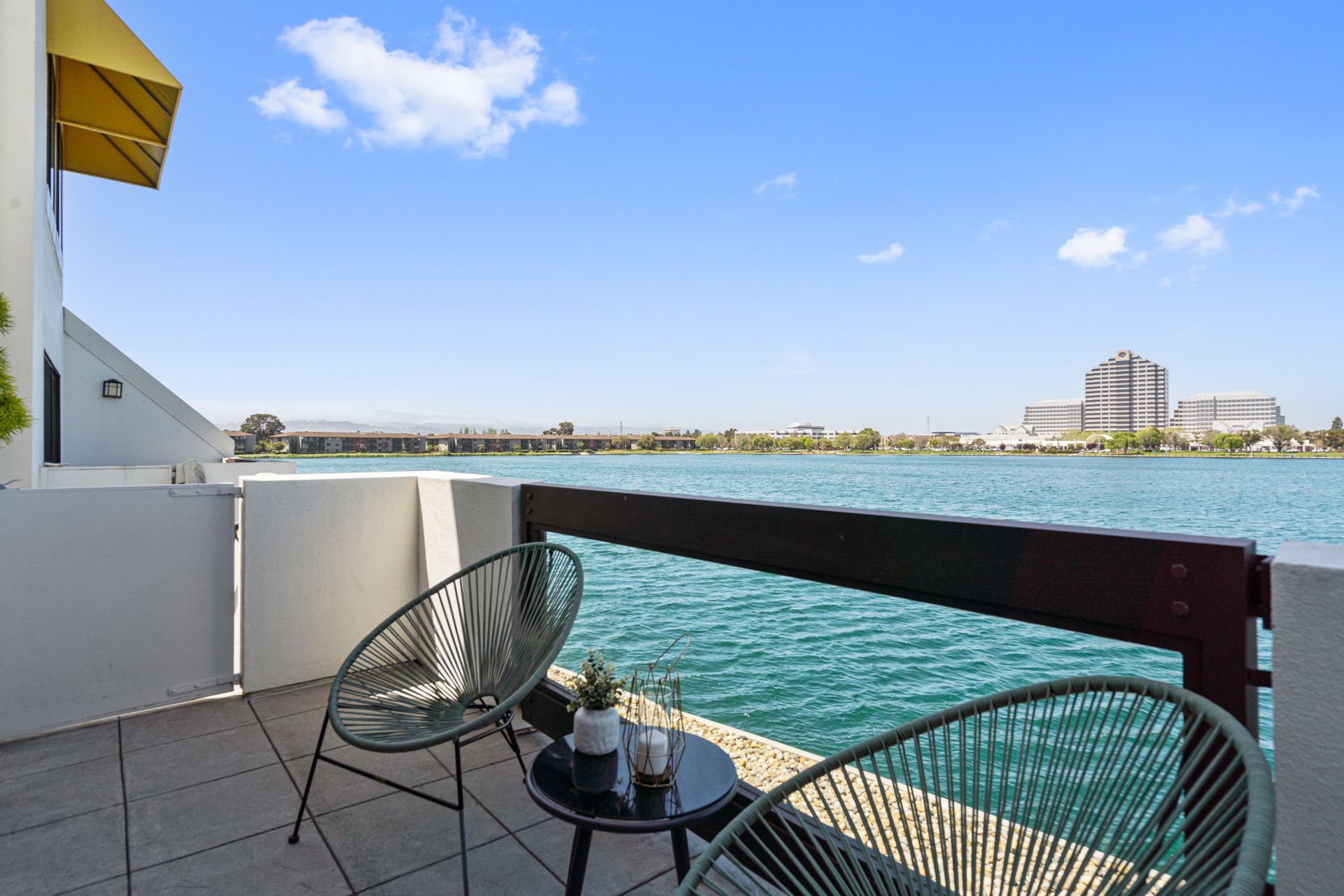 A balcony with two chairs and a table overlooking a body of water.