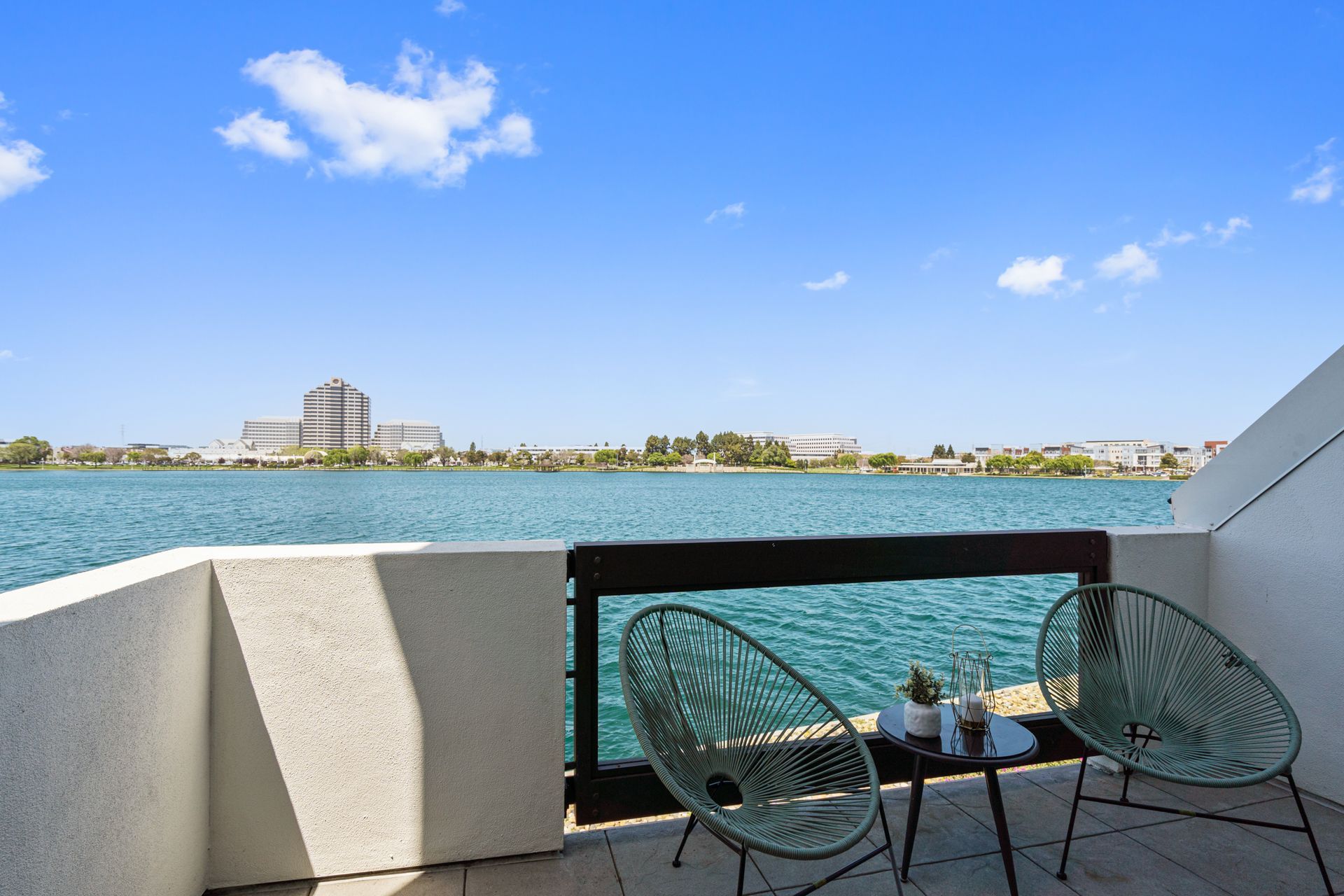 A balcony with two chairs and a table overlooking a lake.