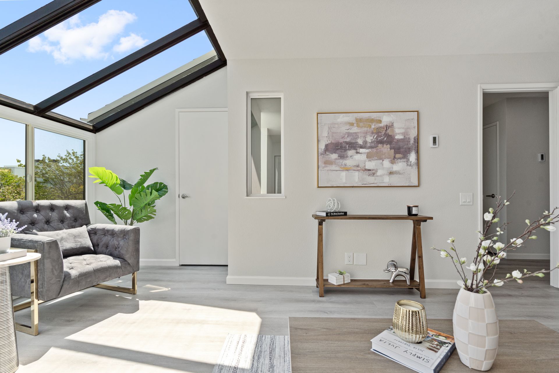 A living room with a couch , chair , table and a skylight.