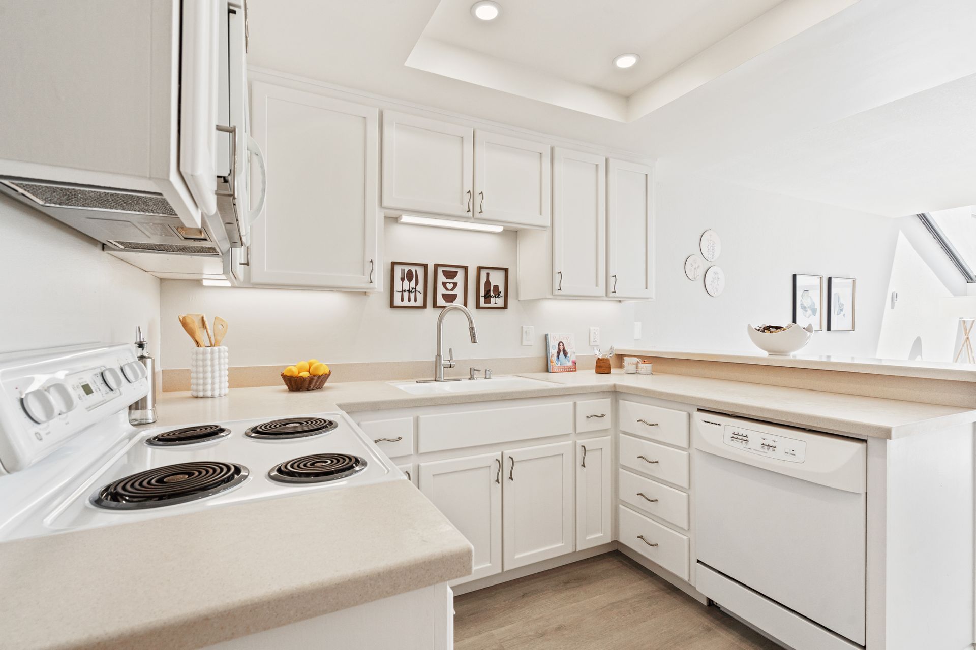 A kitchen with white cabinets , a stove , a dishwasher , and a sink.