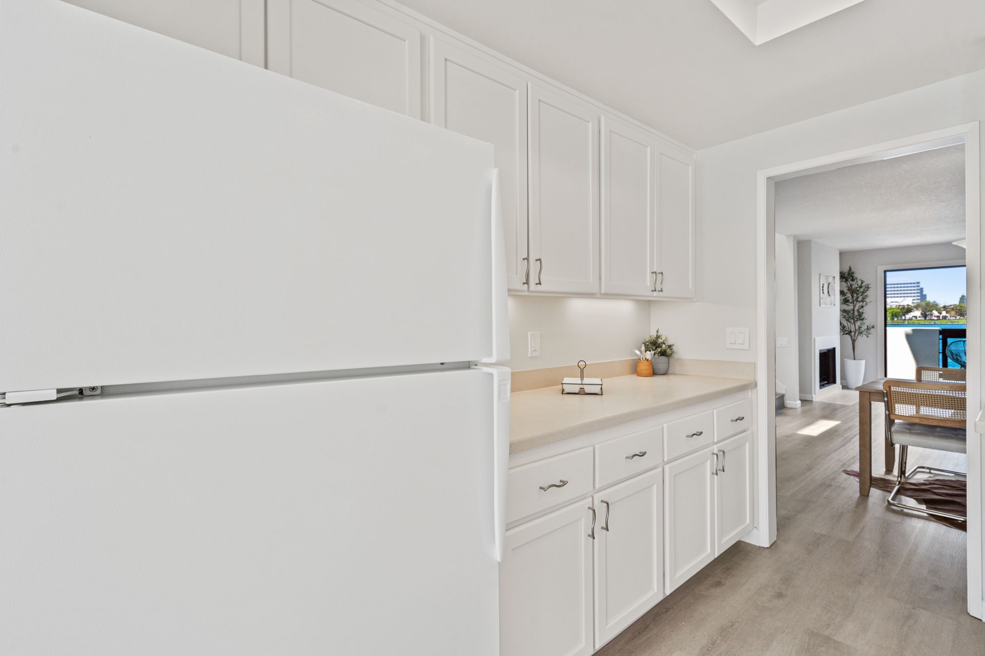A kitchen with white cabinets and a white refrigerator.