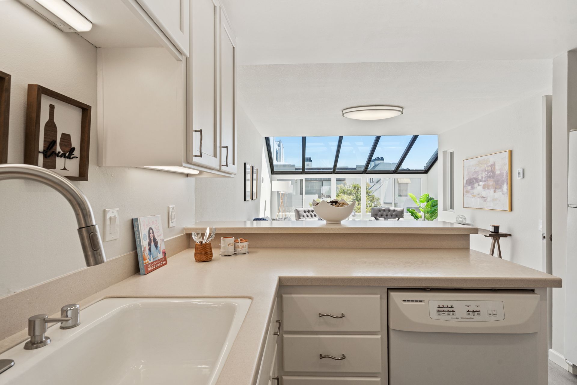 A kitchen with a sink , dishwasher , and window.