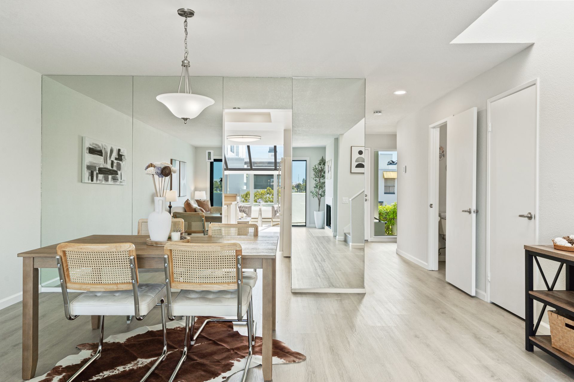 A dining room with a table and chairs and a large mirror on the wall.