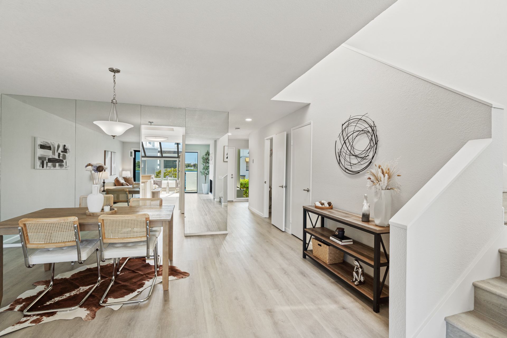 A living room with a table and chairs and stairs leading up to the second floor.