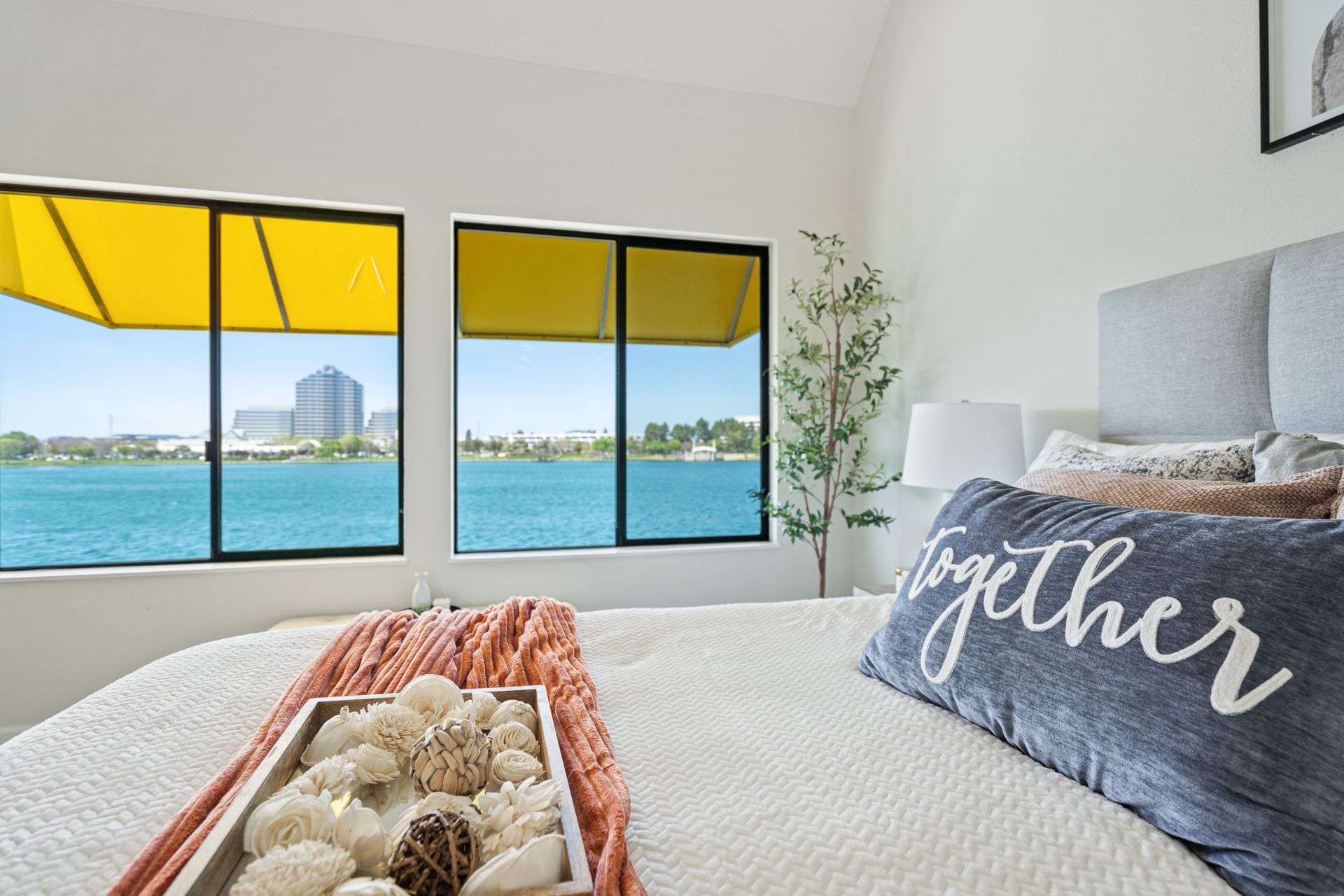 A bedroom with a bed , two windows and a pillow that says `` together ''.