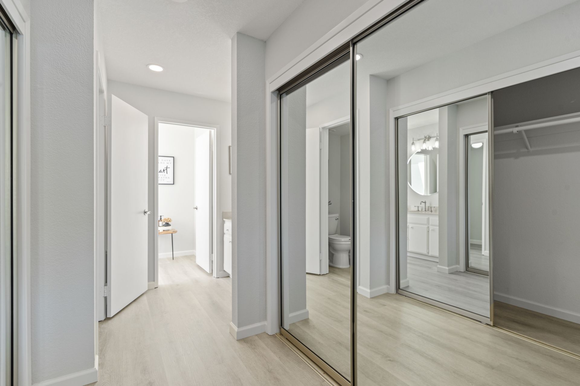 A hallway with sliding glass doors leading to a bathroom and a walk in closet.