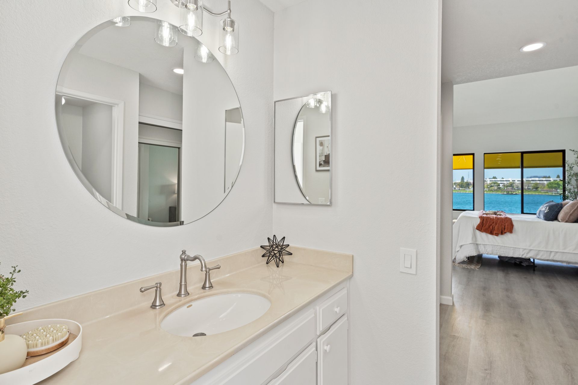 A bathroom with a sink , mirrors and a bed.