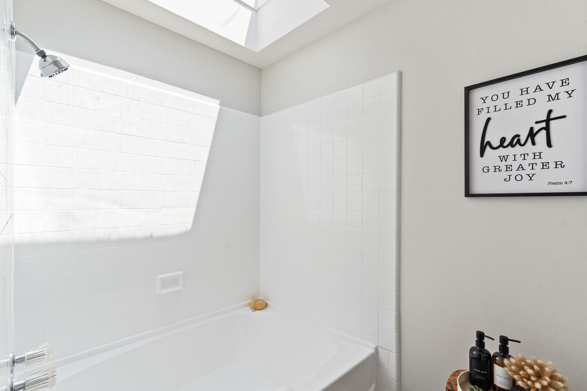 A bathroom with a tub , shower , and skylight.