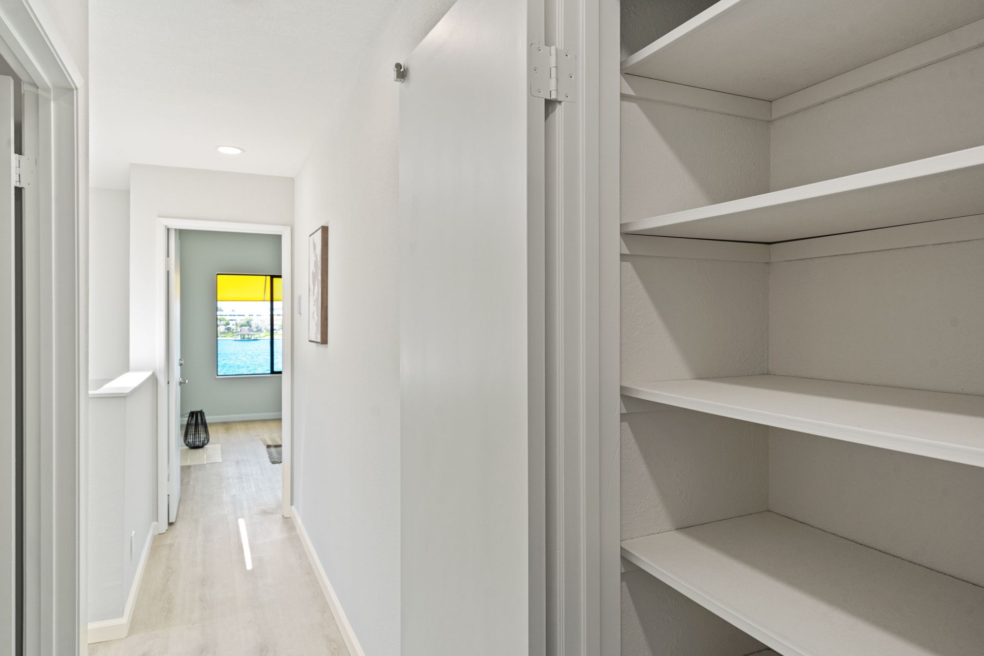 A hallway with empty shelves and a window.