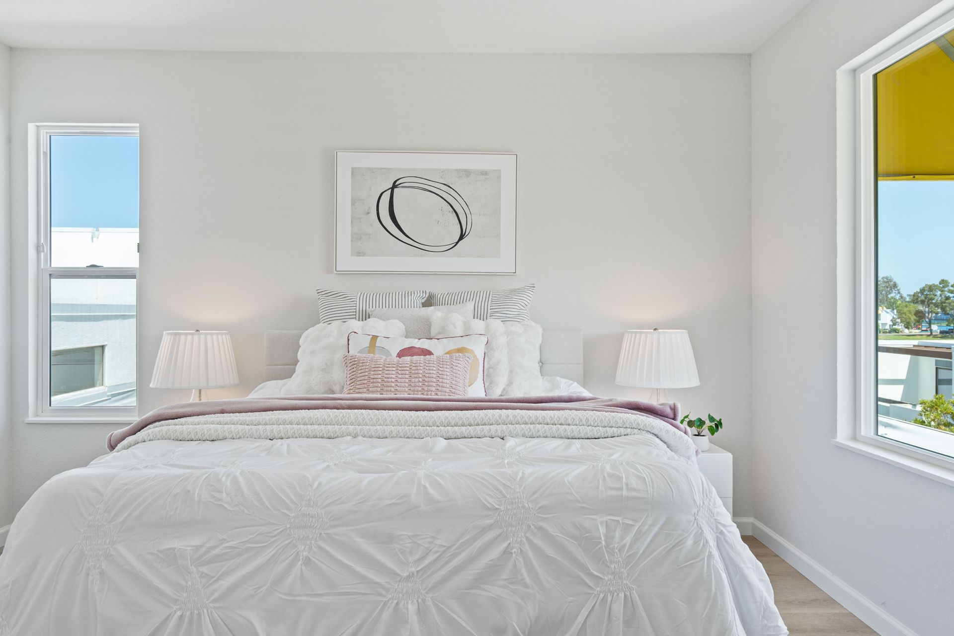 A bedroom with a bed , two windows and a painting on the wall.