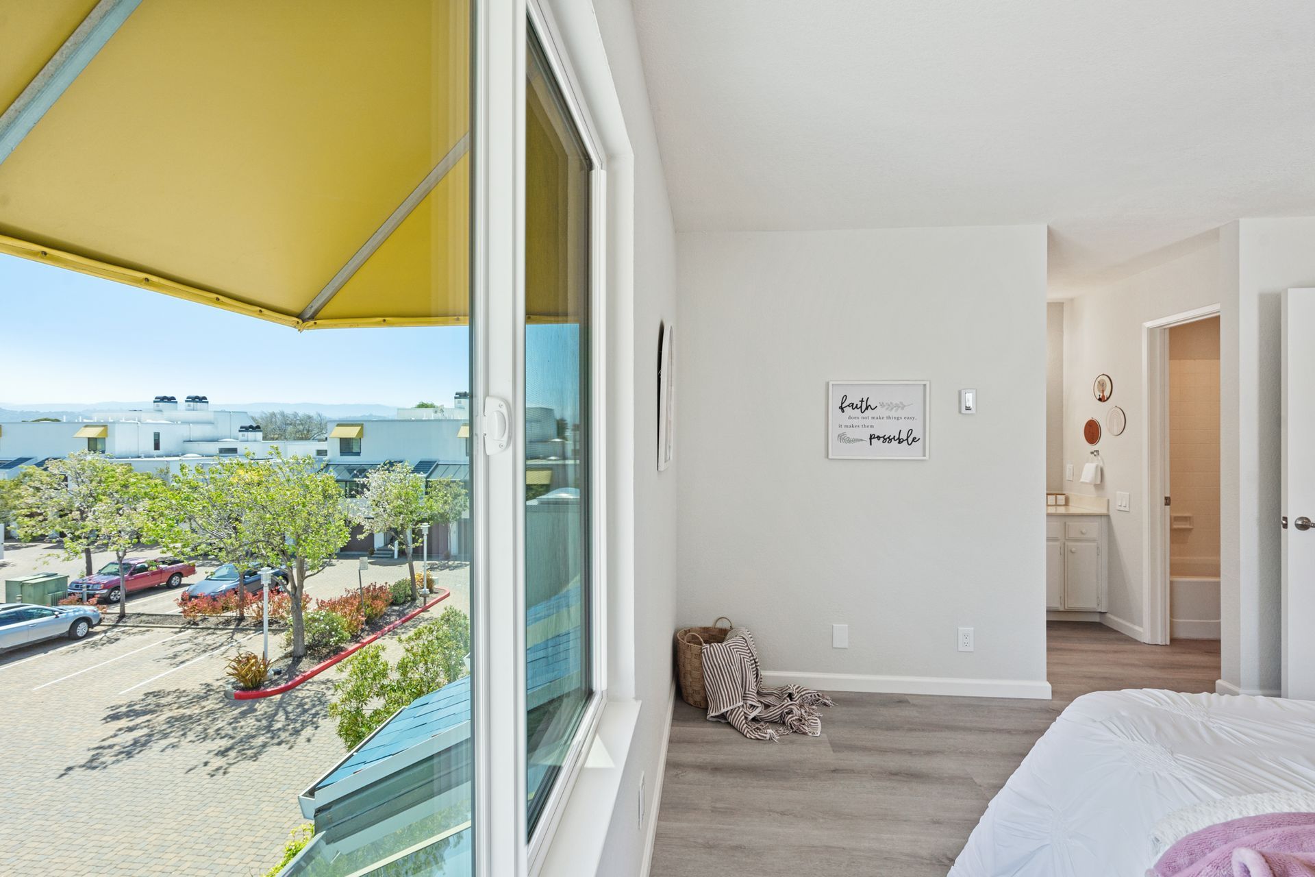 A bedroom with a bed and a large window with a view of a parking lot.