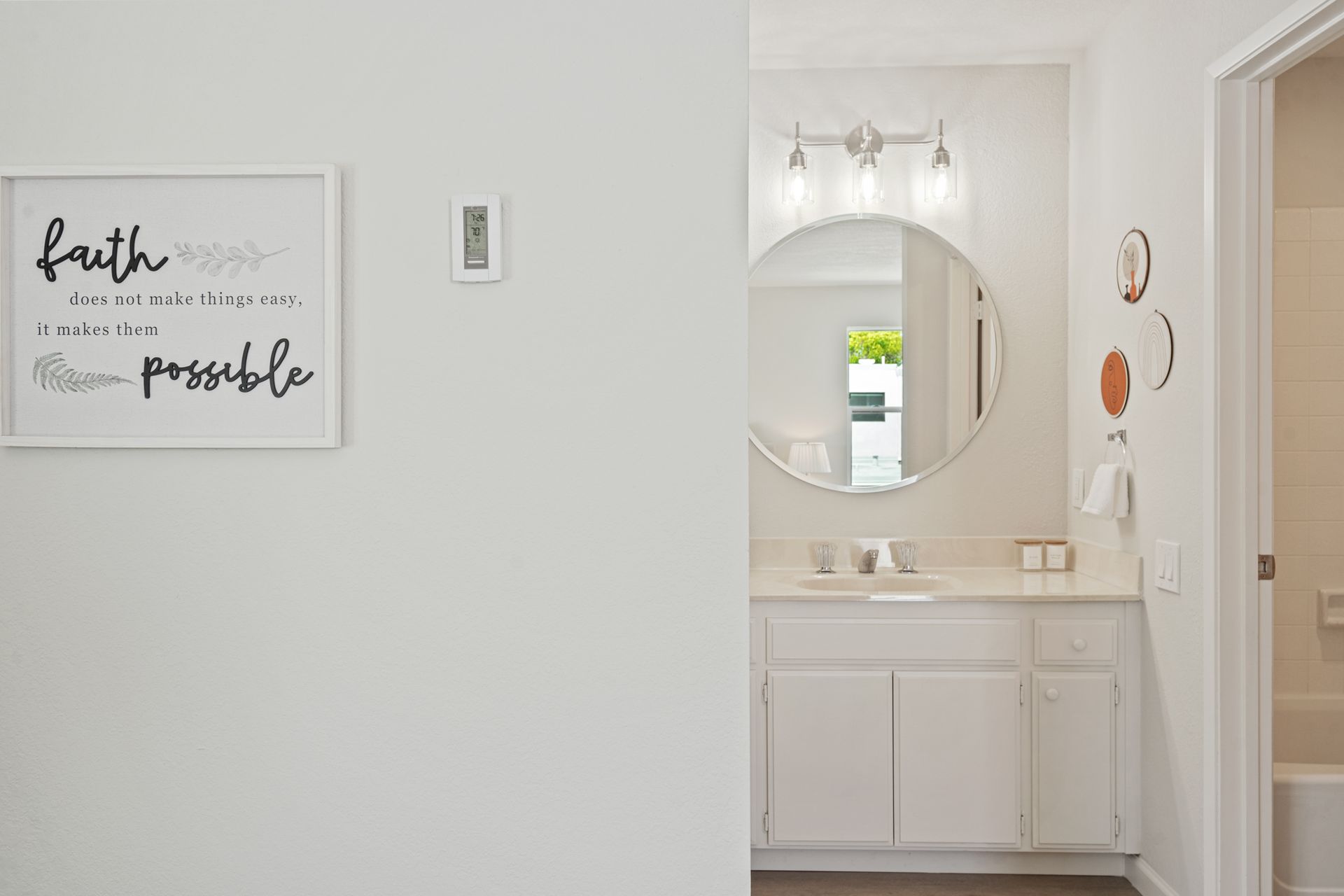 A bathroom with a sink , mirror and a sign on the wall.