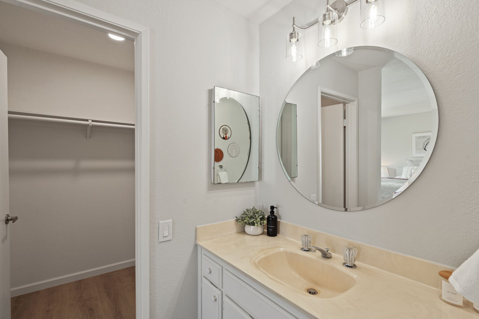 A bathroom with a sink , mirror and walk in closet.