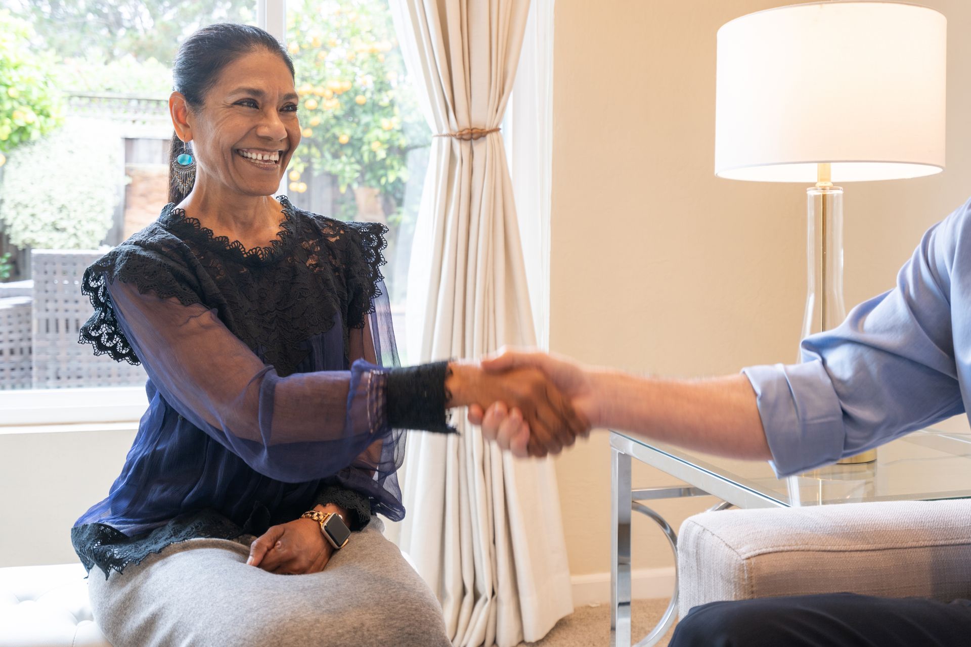 A woman is shaking hands with a man while sitting on a couch.