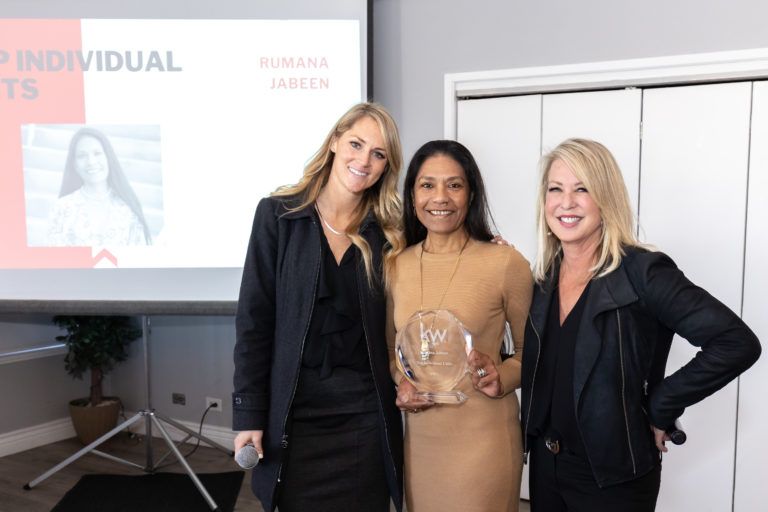 Three women are posing for a picture in front of a projector screen.