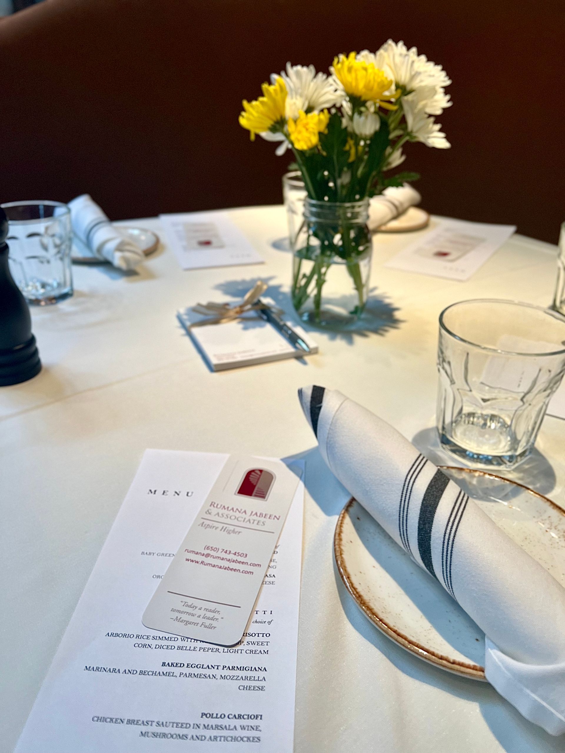 A table with a menu and flowers on it