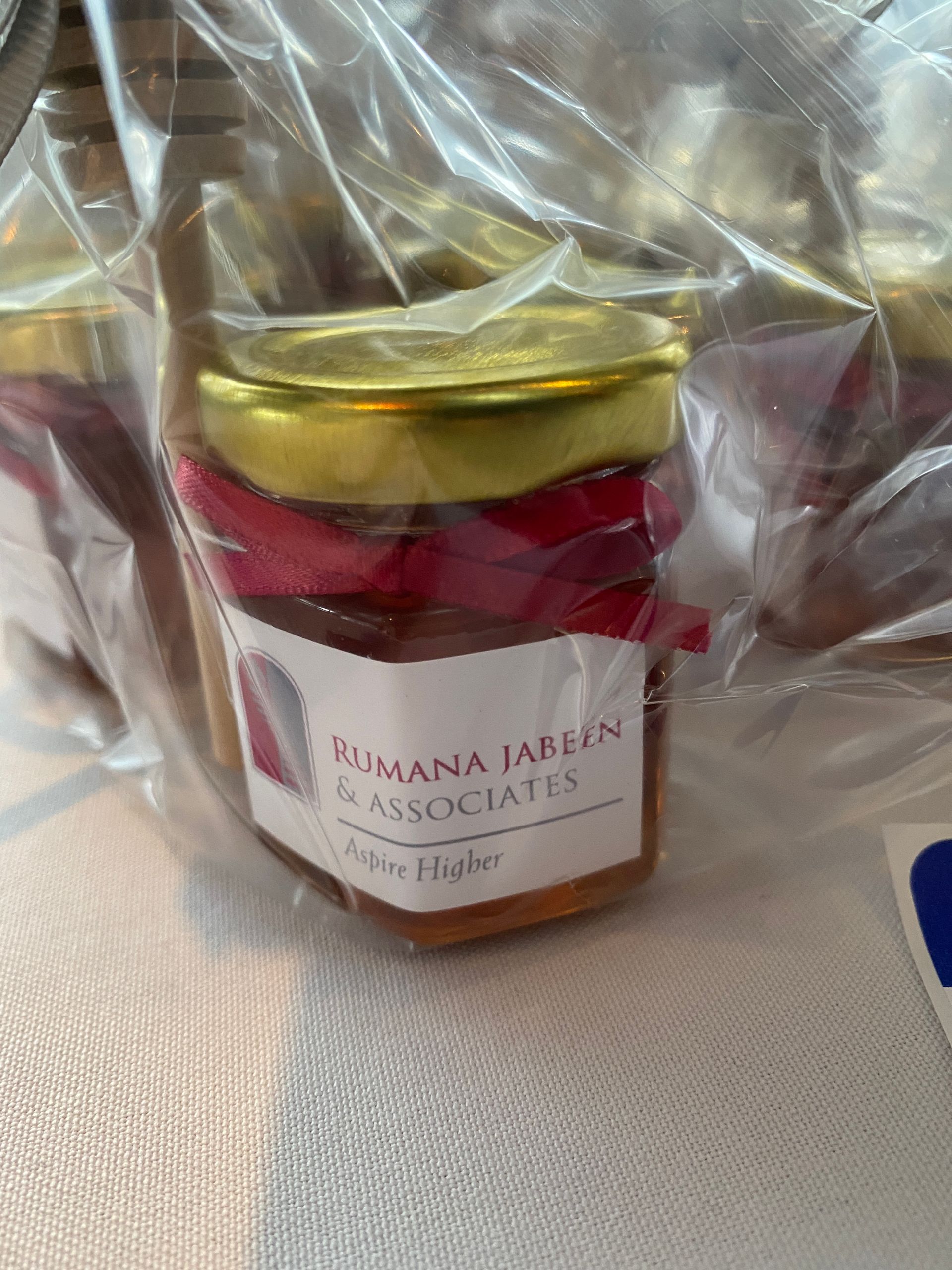 A jar of jam is wrapped in plastic and sitting on a table.