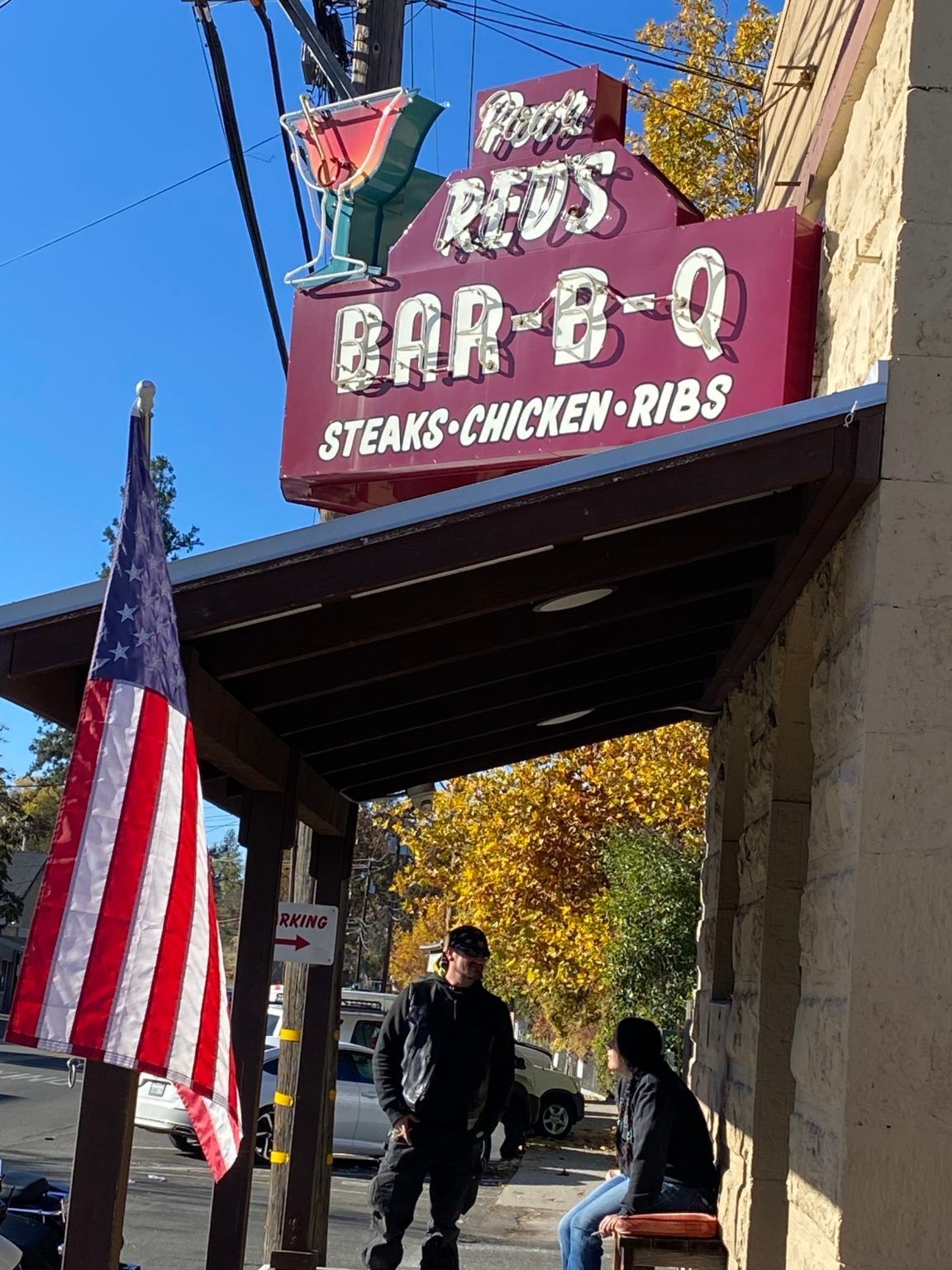 A red sign that says bar-b-q steaks chicken ribs