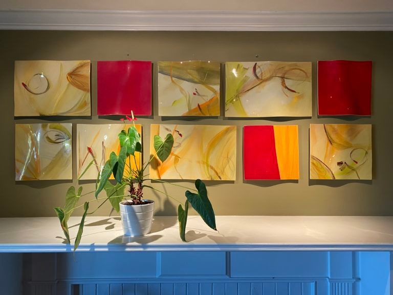 A potted plant is sitting on a table in front of a wall of paintings.