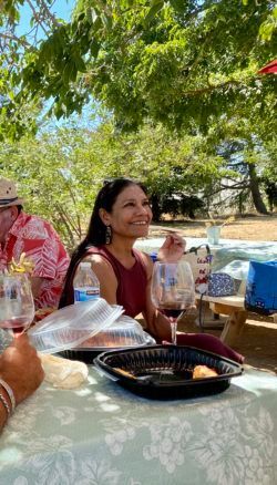 A woman is sitting at a table with a glass of wine.