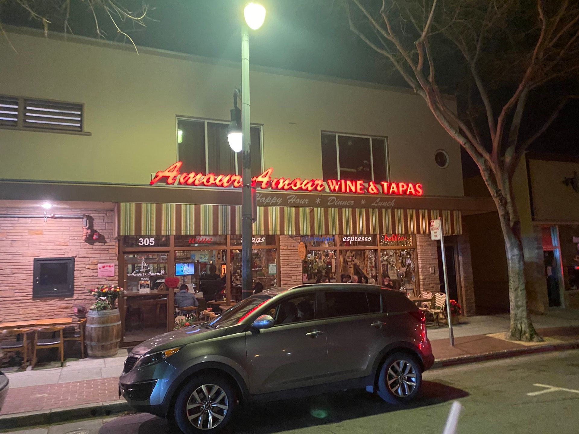 A car is parked in front of a restaurant at night.
