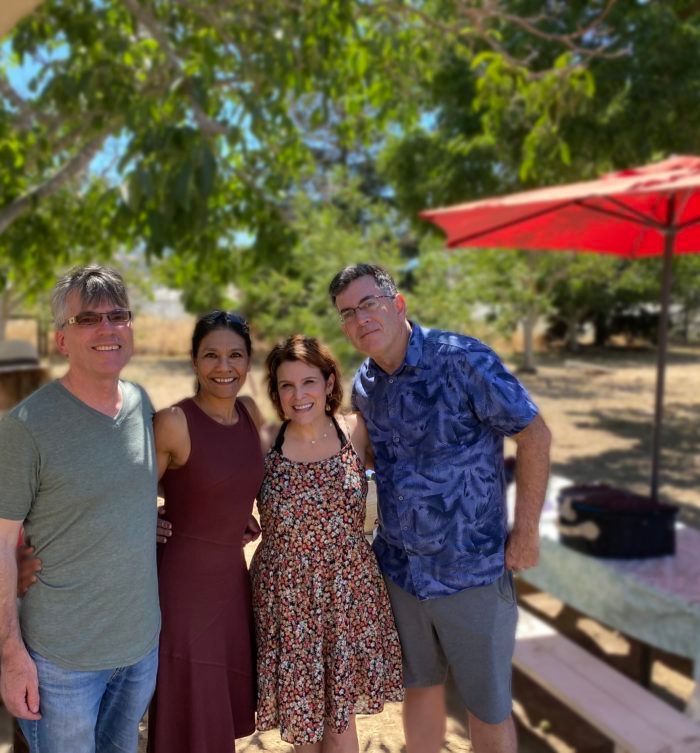 A group of people are posing for a picture in front of a red umbrella.
