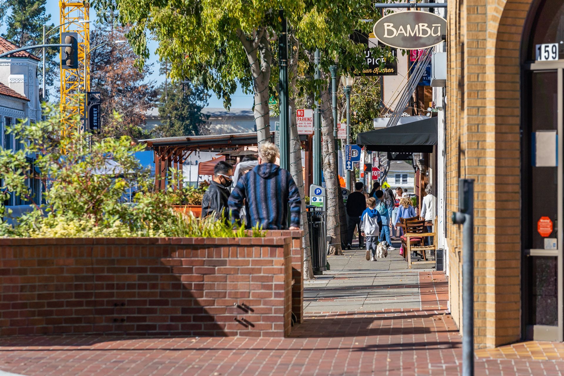 A man is walking down a brick sidewalk in front of a building.