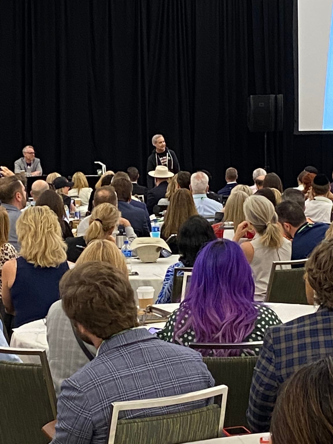 A large group of people are sitting at tables in a conference room.
