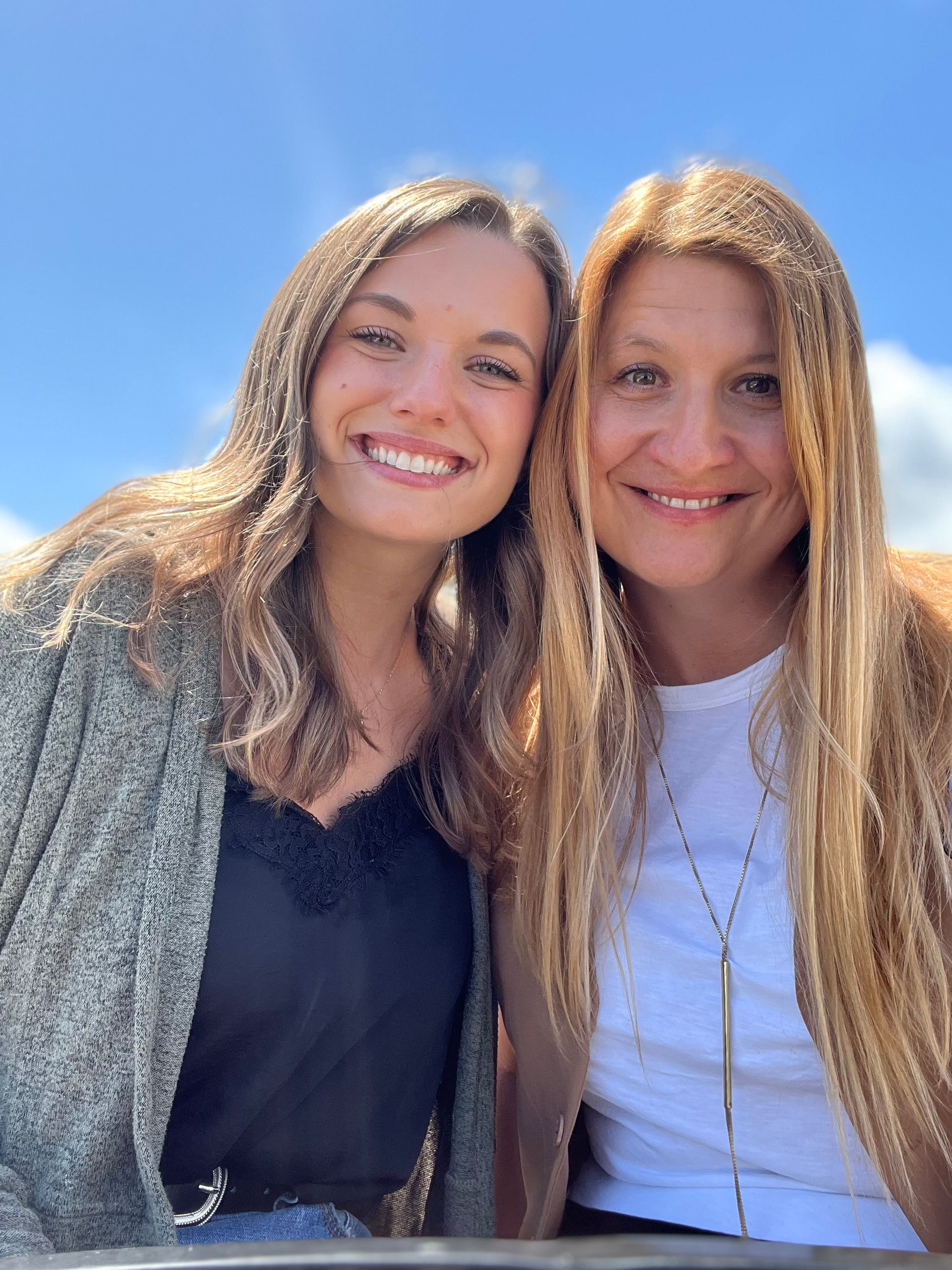 Two women are posing for a picture together and smiling for the camera.