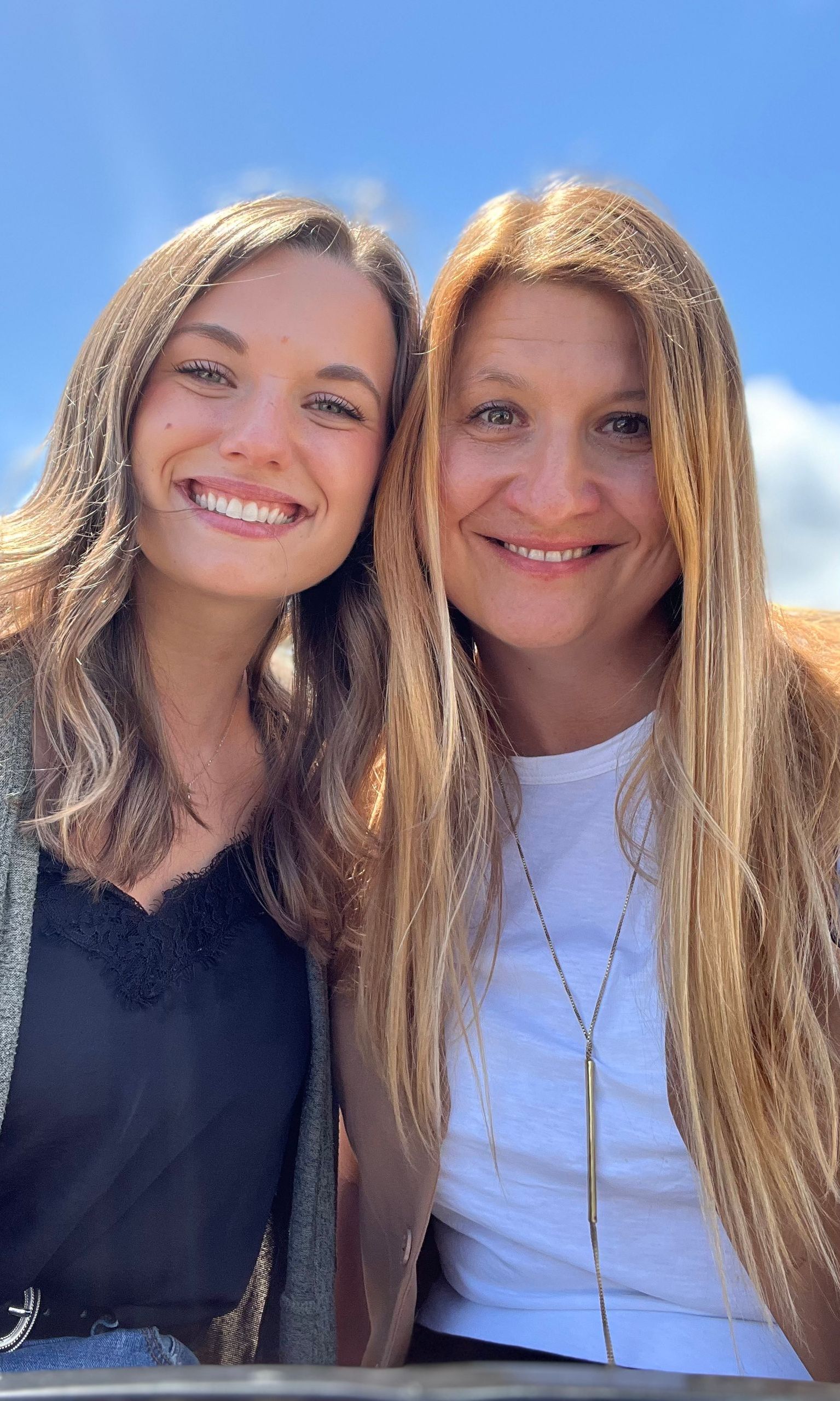 Two women are posing for a picture together and smiling for the camera.