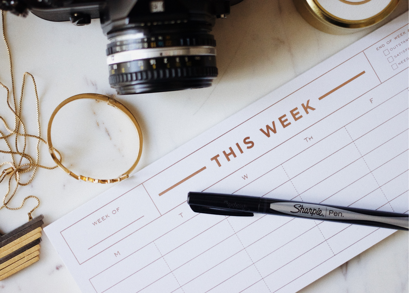 A pen is sitting on top of a calendar that says this week.