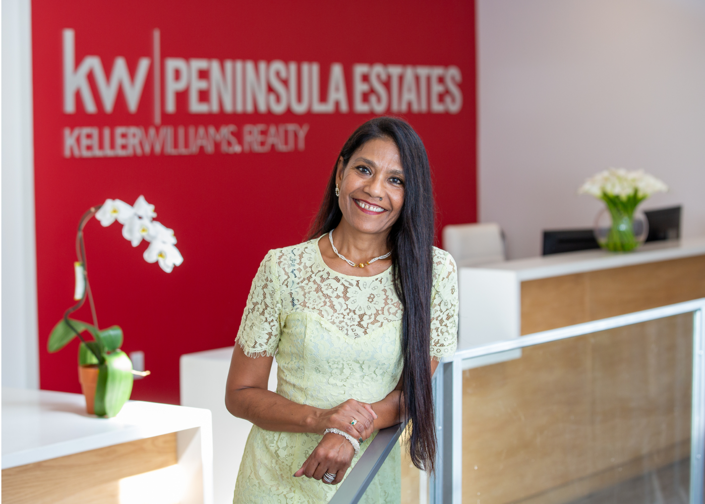 A woman is standing in front of a kw peninsula estates sign