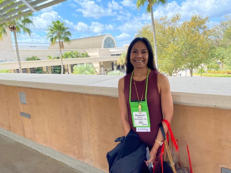 A woman wearing a name tag is standing in front of a building.