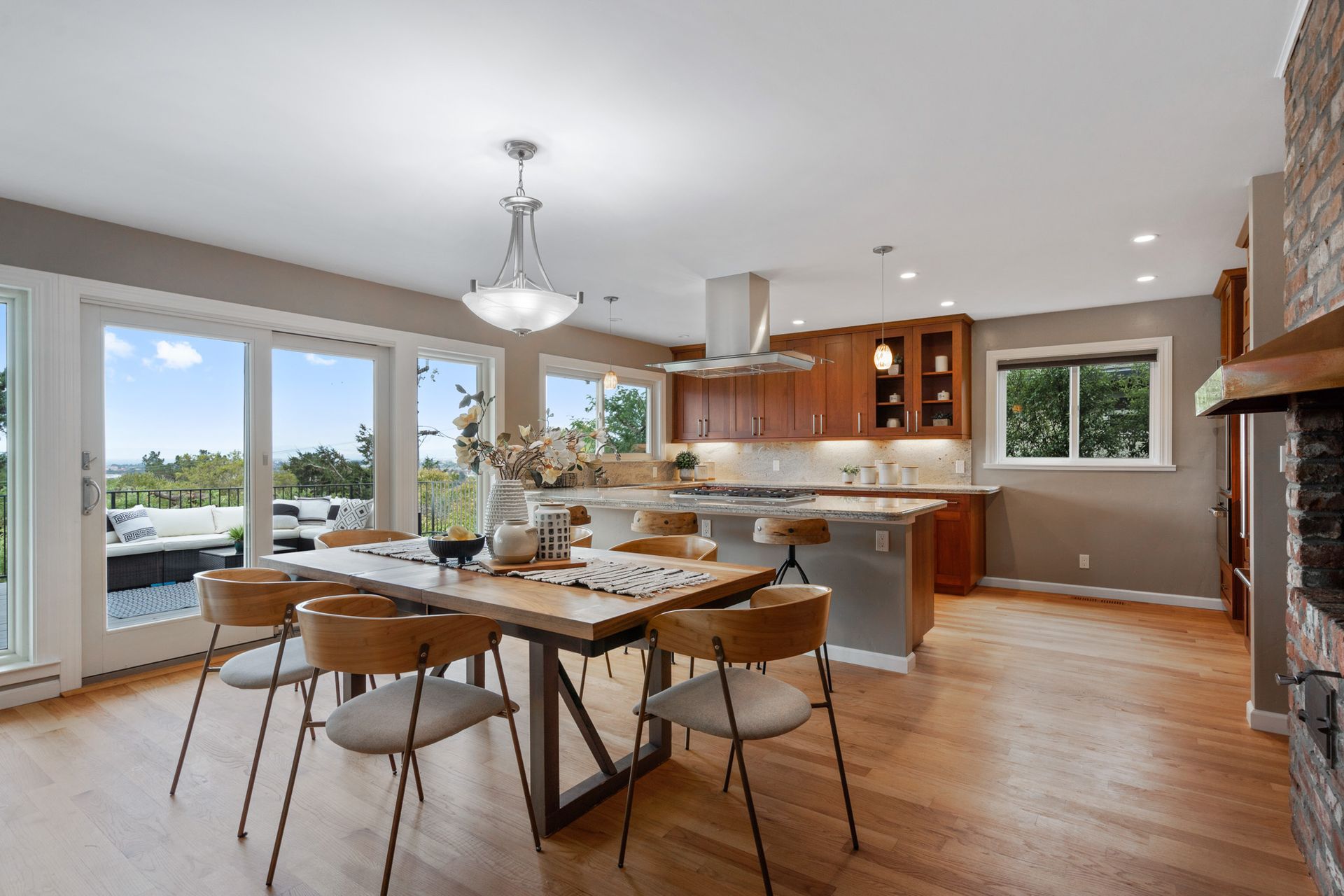 A dining room with a table and chairs and a kitchen in the background.