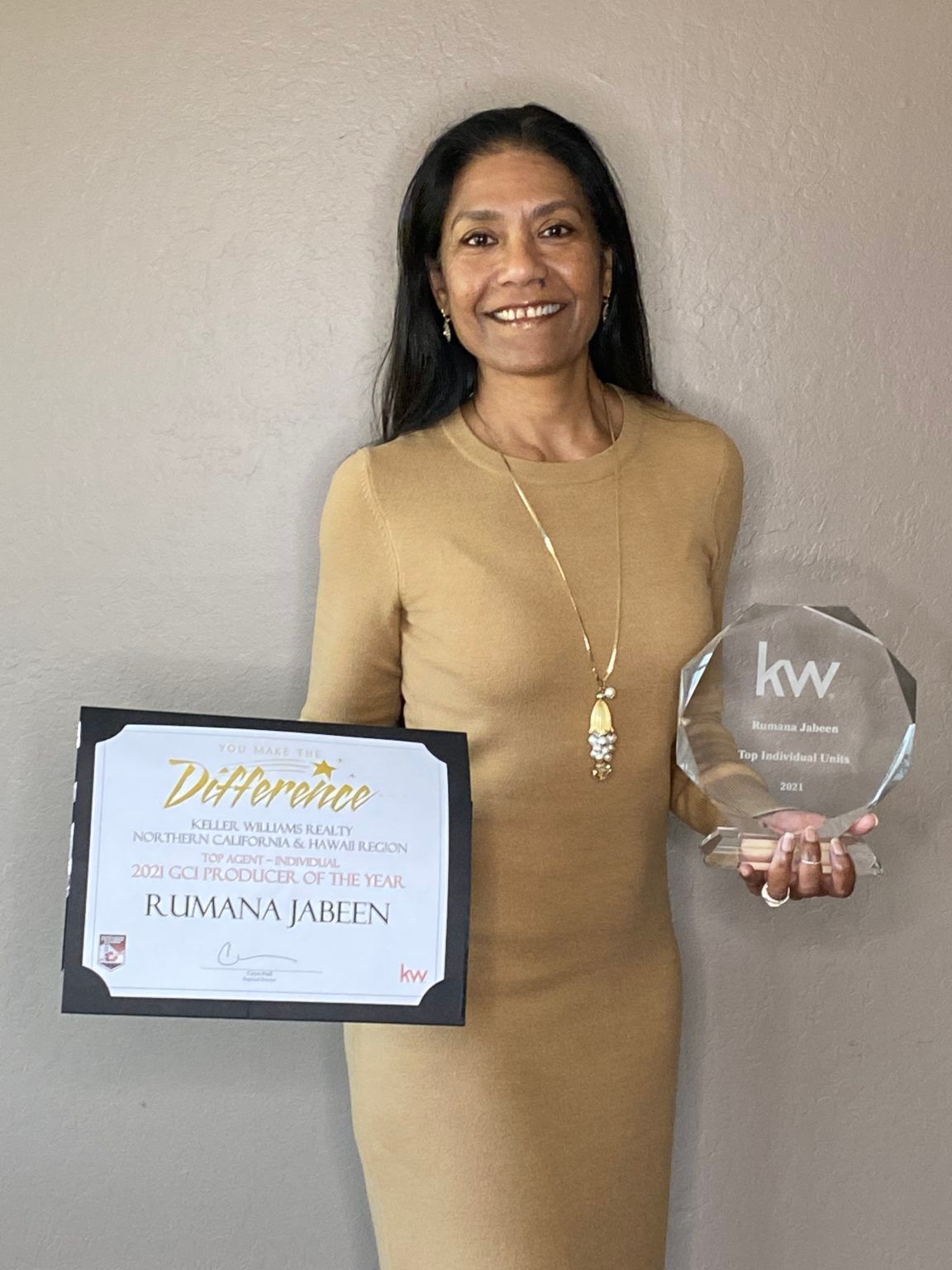 A woman is holding a certificate and a trophy.