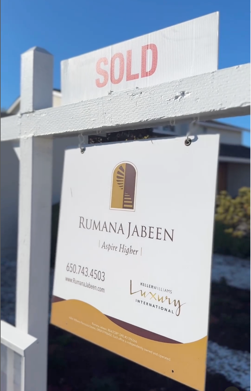 A sold sign is attached to a white fence