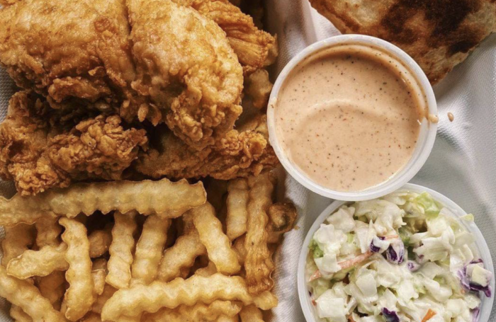 There is a plate of fried chicken , french fries , and coleslaw.