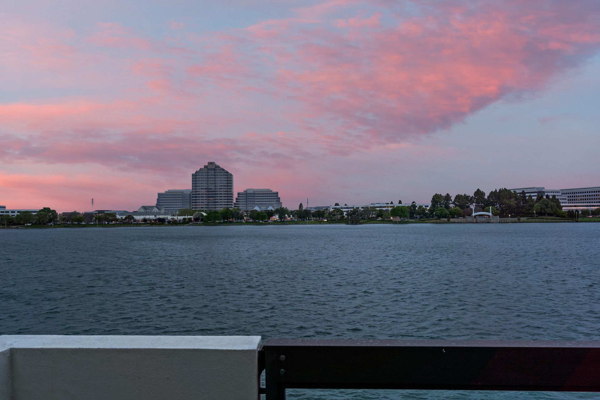 A large body of water with a city in the background at sunset.