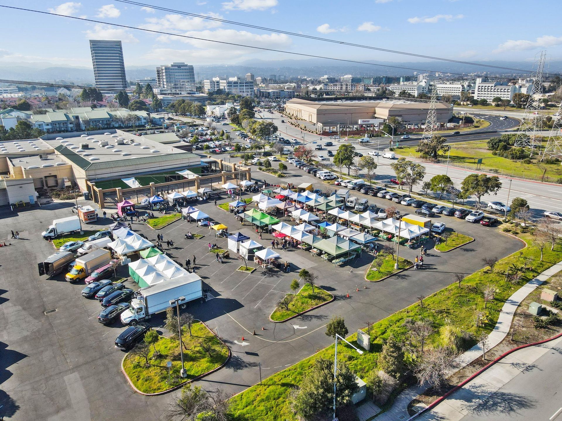 An aerial view of a parking lot filled with cars and tents