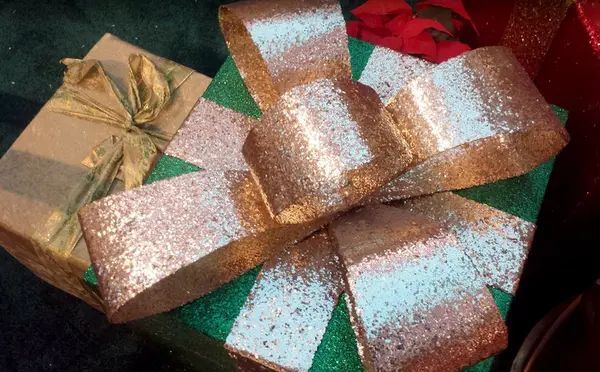 A green gift box with a gold bow on top of it.