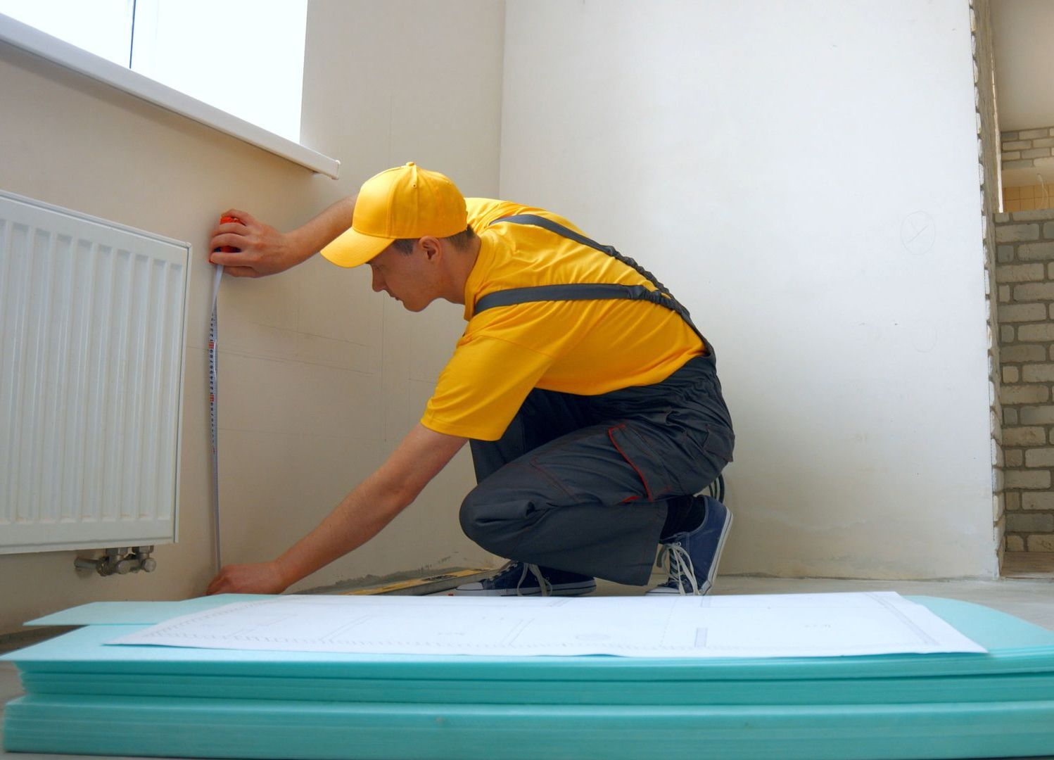A man is measuring a radiator with a tape measure