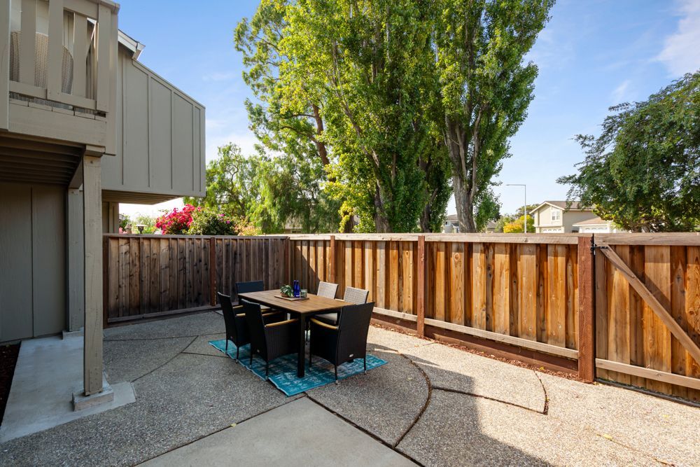 Private backyard patio with wood fencing and direct access to landscaped community greenbelt, listed with Foster City Realtor Rumana Jabeen.
