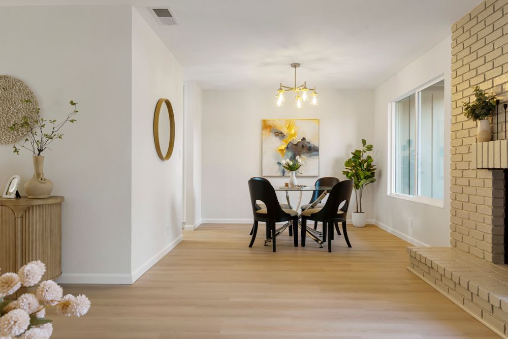 Dining area with chandelier and greenbelt views, offering natural light and an inviting atmosphere, presented by Rumana Jabeen Real Estate.