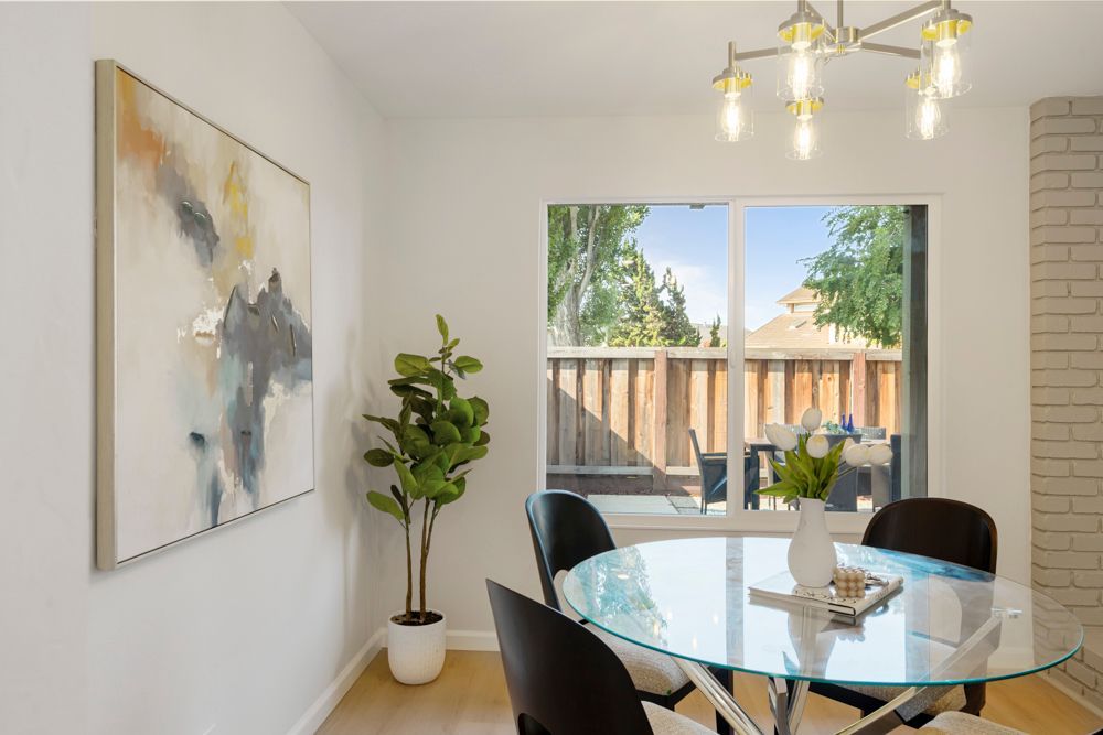 Dining area with chandelier and greenbelt views, offering natural light and an inviting atmosphere, presented by Rumana Jabeen Real Estate.